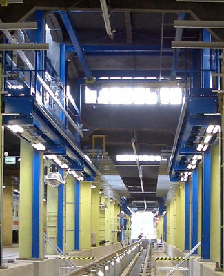 Vista inferior de conjunto de una plataforma de trabajo suspendida donde se puede apreciar el seguro anticaídas, el sistema de iluminación integrado y el puente grúa monorraíl.