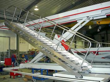 Plataforma de trabajo en proceso de construcción, con escalera de aluminio corredera en primer plano.